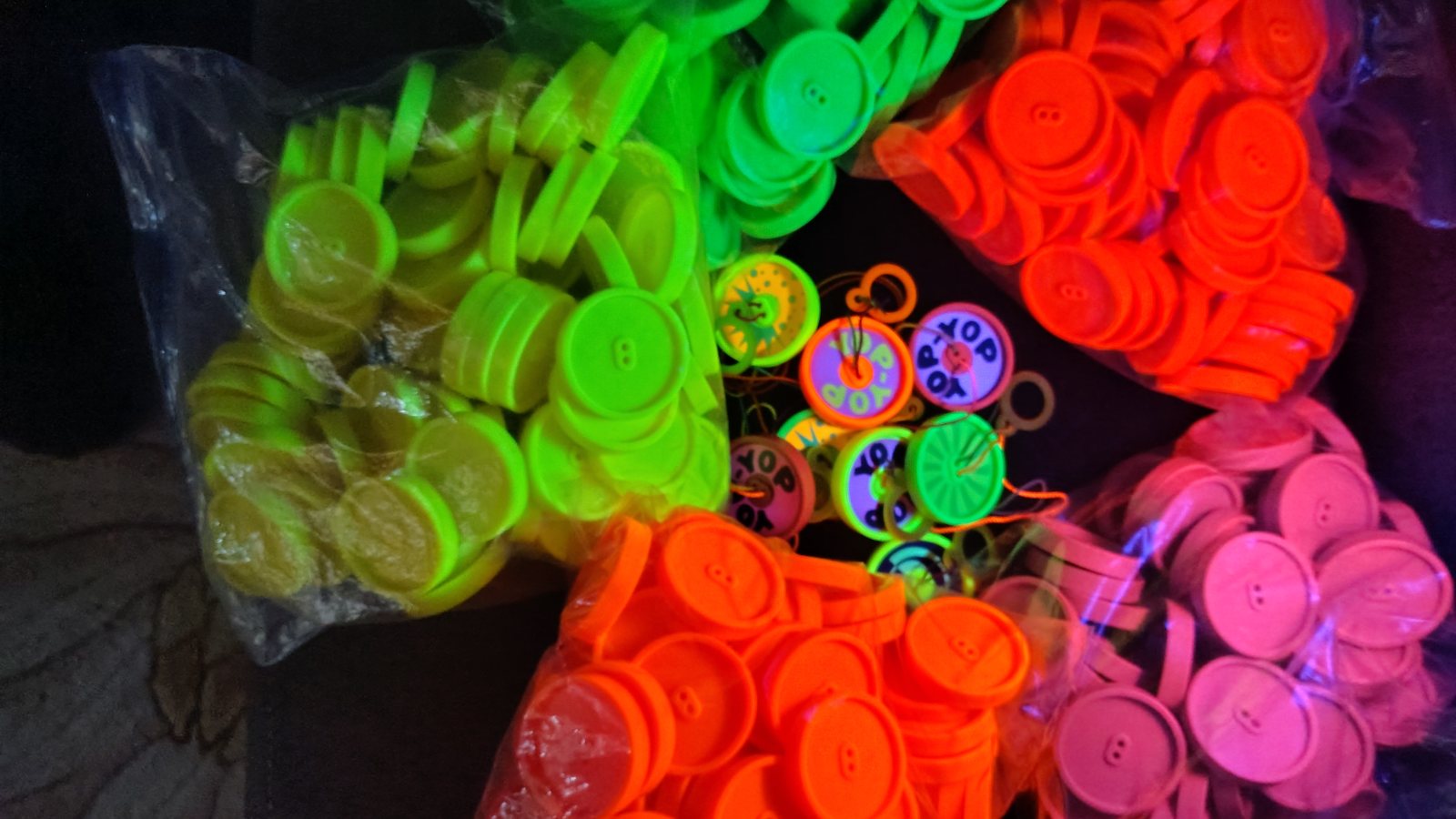 Bags of fluorescent discs around finished Yop-Yops, glowing under blacklight